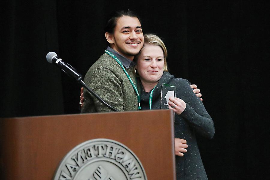 十大彩票网赌平台 student Pablo Garcia presents the 十大彩票网赌平台桥梁奖 to Huron High School counselor Caitlin Van Cleve.